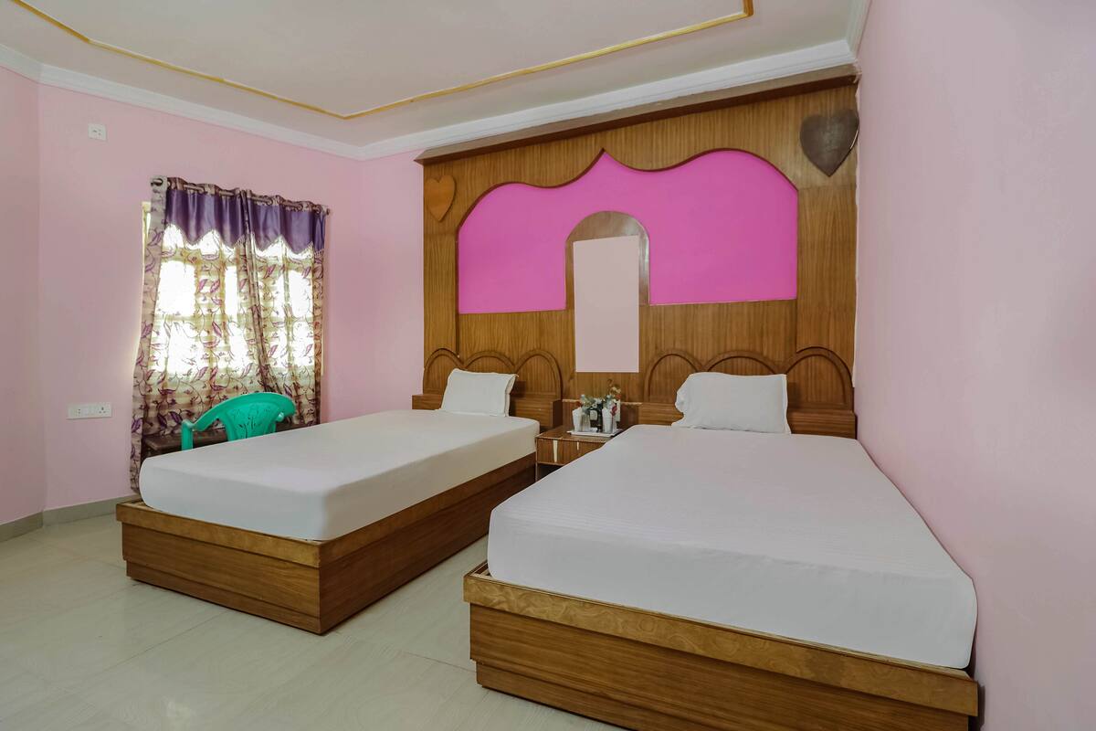 A hotel room with two wooden beds, a nightstand, a mirror, and a window with curtains.