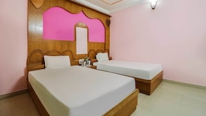 Ein Hotelzimmer mit zwei Betten, Holz-Kopfteilen, einem großen Spiegel und einer Wand in Rosa.