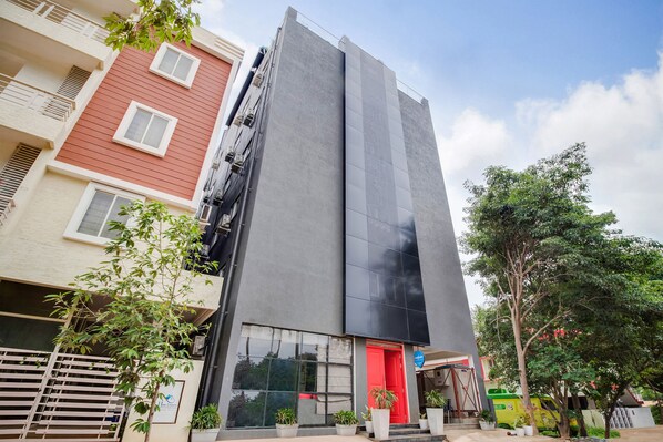 A modern building with a red door, large windows, and a balcony.