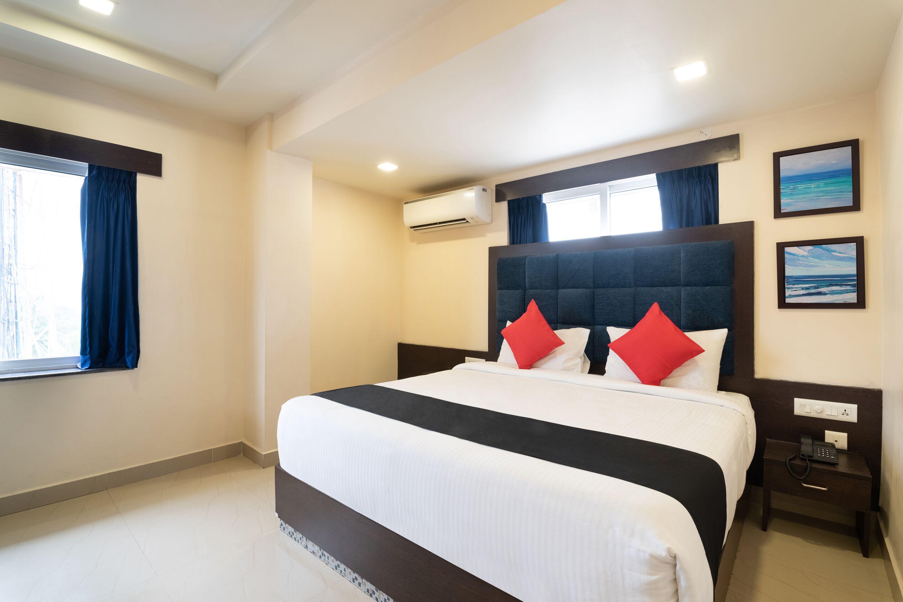 A hotel room with a large bed, a bedside table with a phone, and a window with curtains.