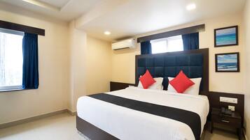 A hotel room with a large bed, a bedside table with a phone, and a window with curtains.