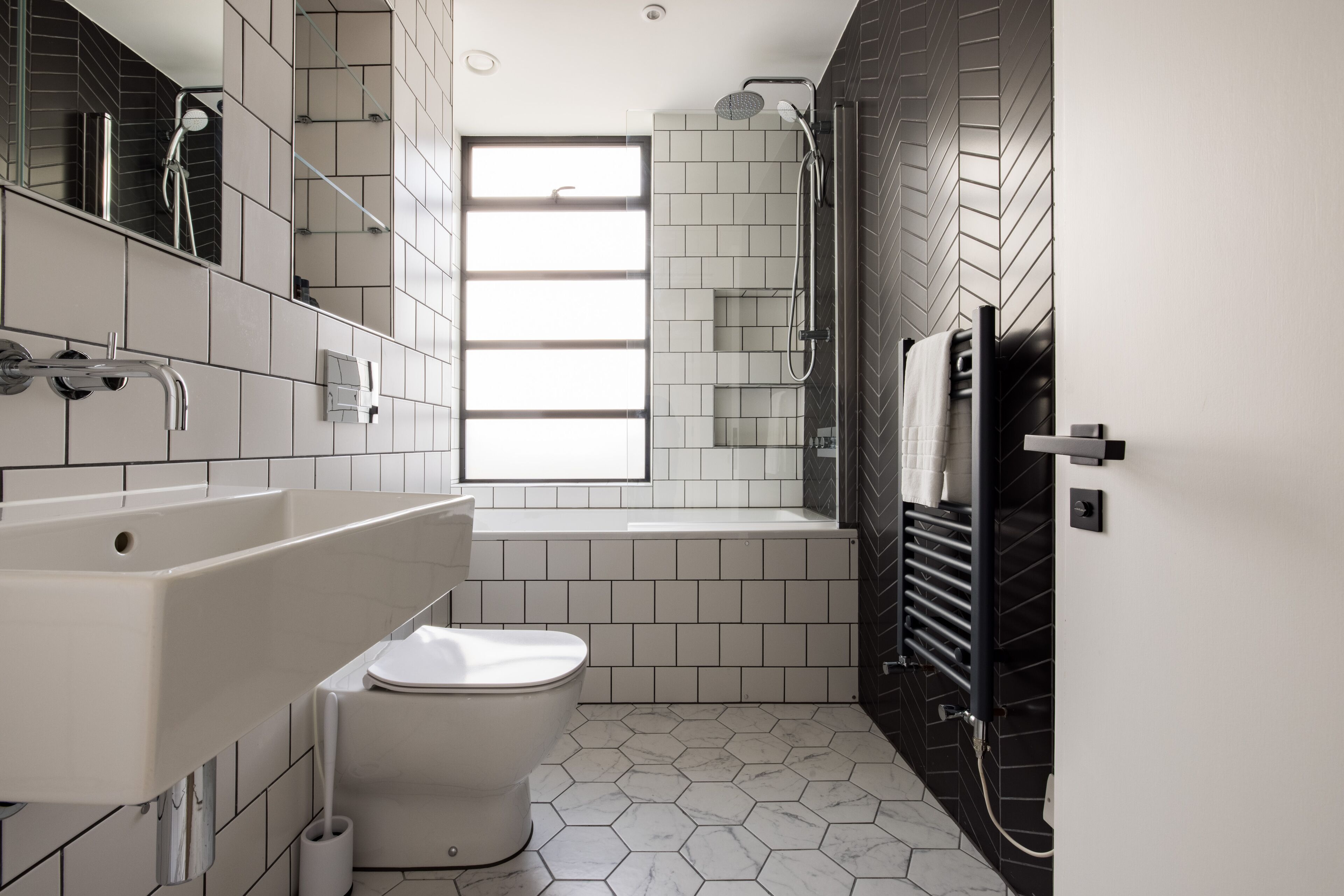 Ein modernes Badezimmer mit Toilette, großem Waschbecken, Badewanne und Dusche.