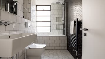 Ein modernes Badezimmer mit Toilette, großem Waschbecken, Badewanne und Dusche.