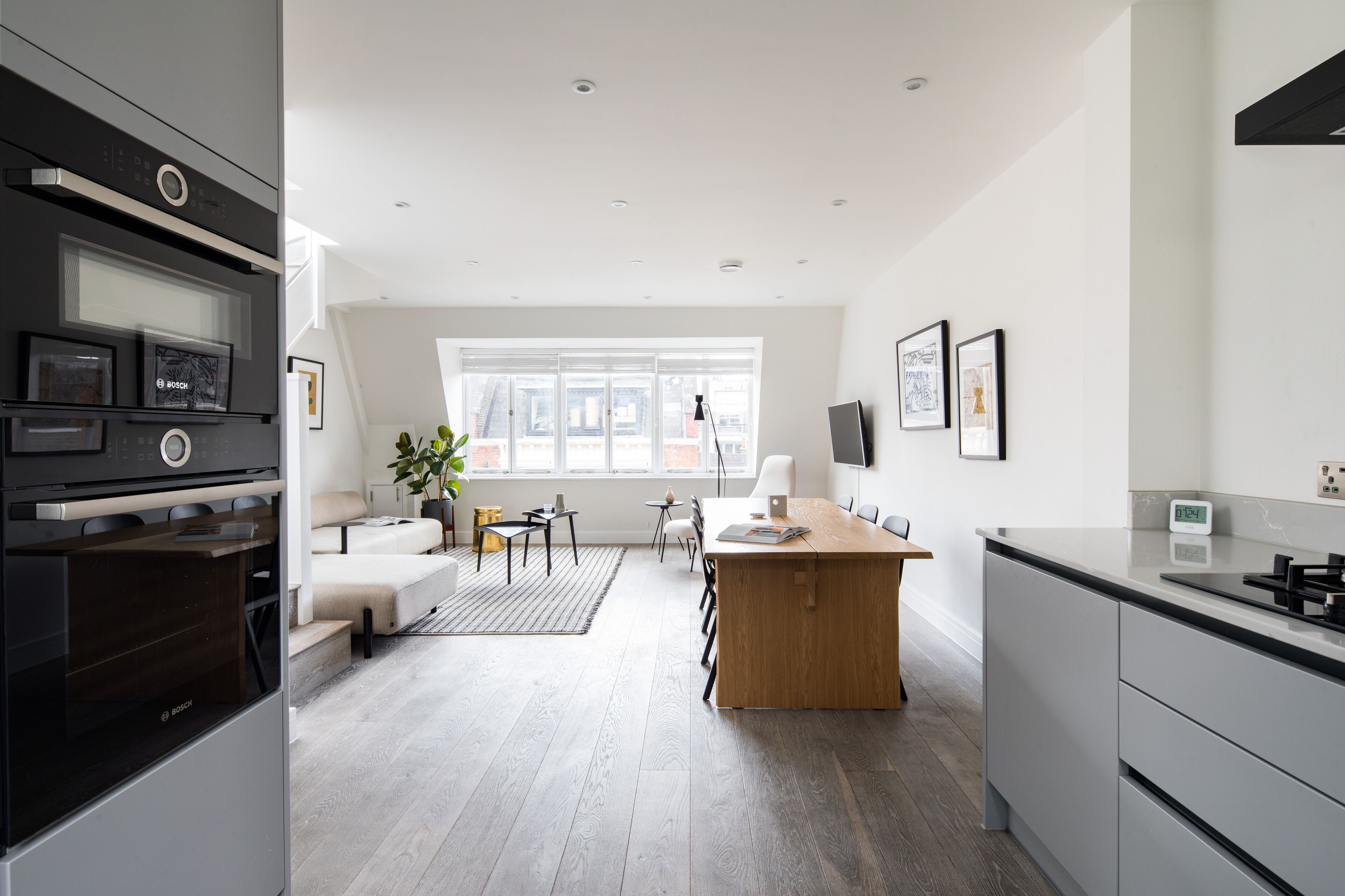 Una cocina moderna con horno Bosch, una mesa de comedor de madera y un amplio ventanal que proporciona luz natural.