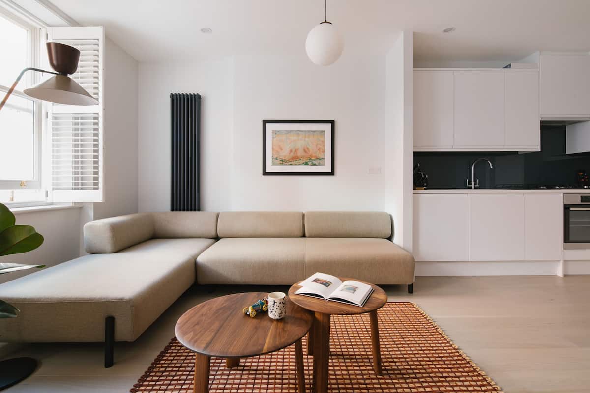 A modern living room with a sectional sofa, a wooden coffee table, and a kitchen area in the background.