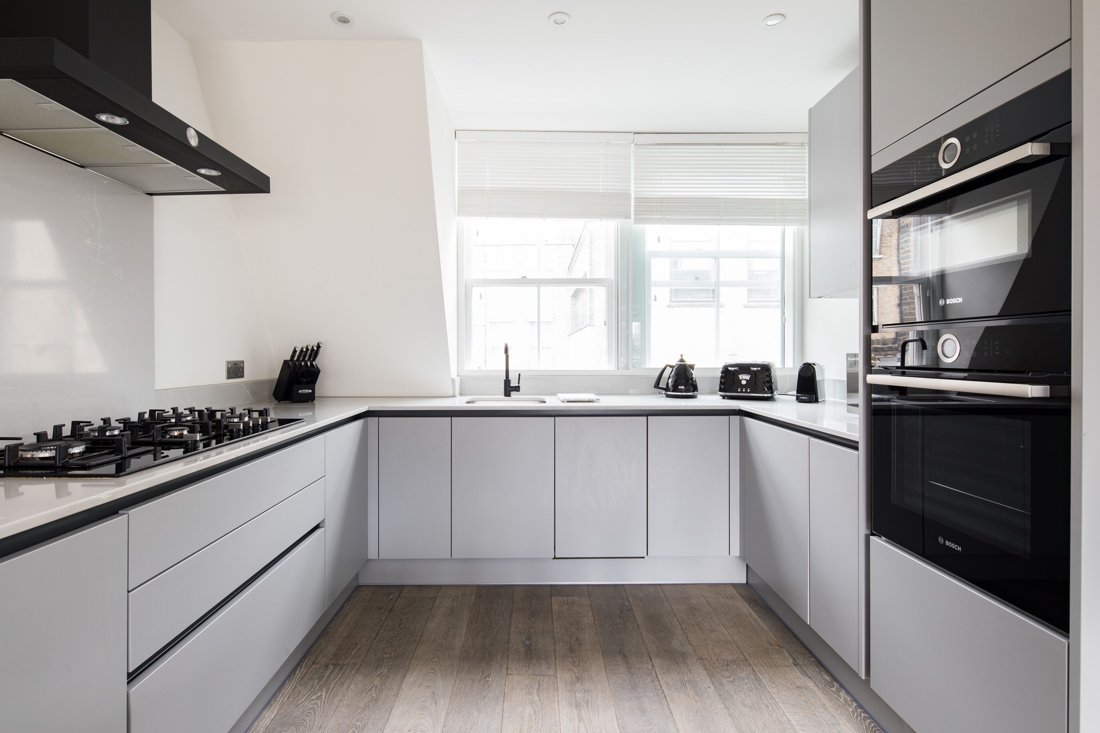 A modern kitchen with white cabinets, a black stove, and a Bosch oven.