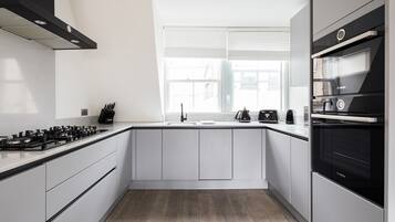 A modern kitchen with white cabinets, a black stove, and a Bosch oven.