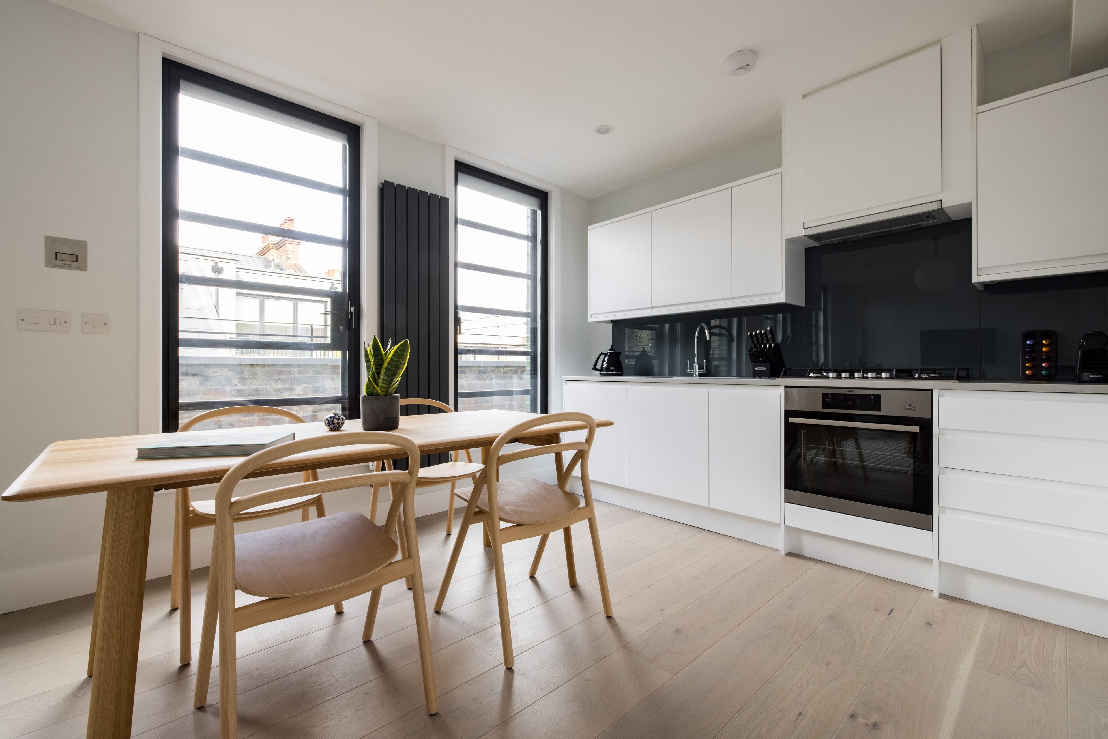 Una cocina moderna con armarios blancos, una mesa de comedor de madera y dos sillas.