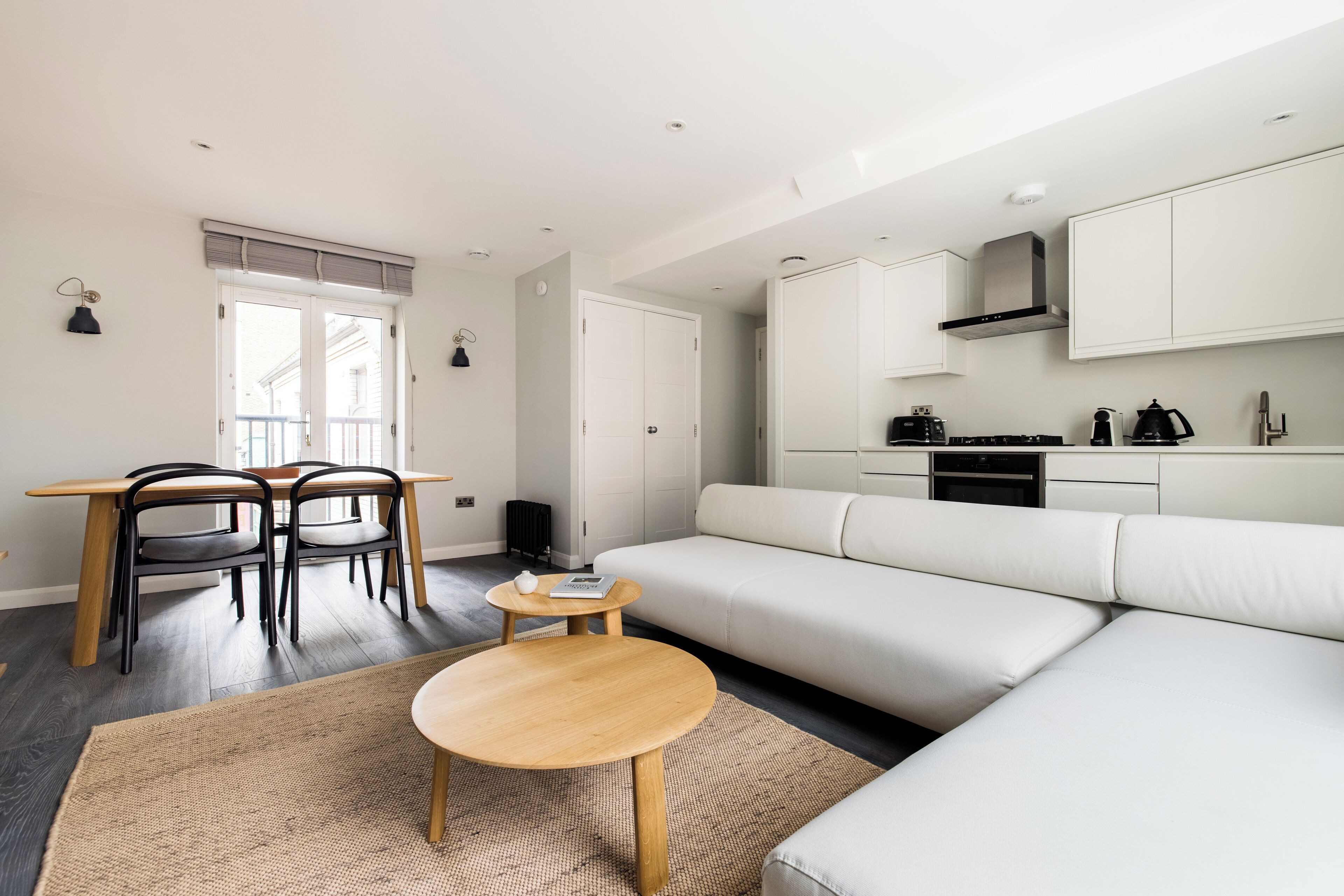 A modern living room with a sofa, a dining table with chairs, and a small coffee table.