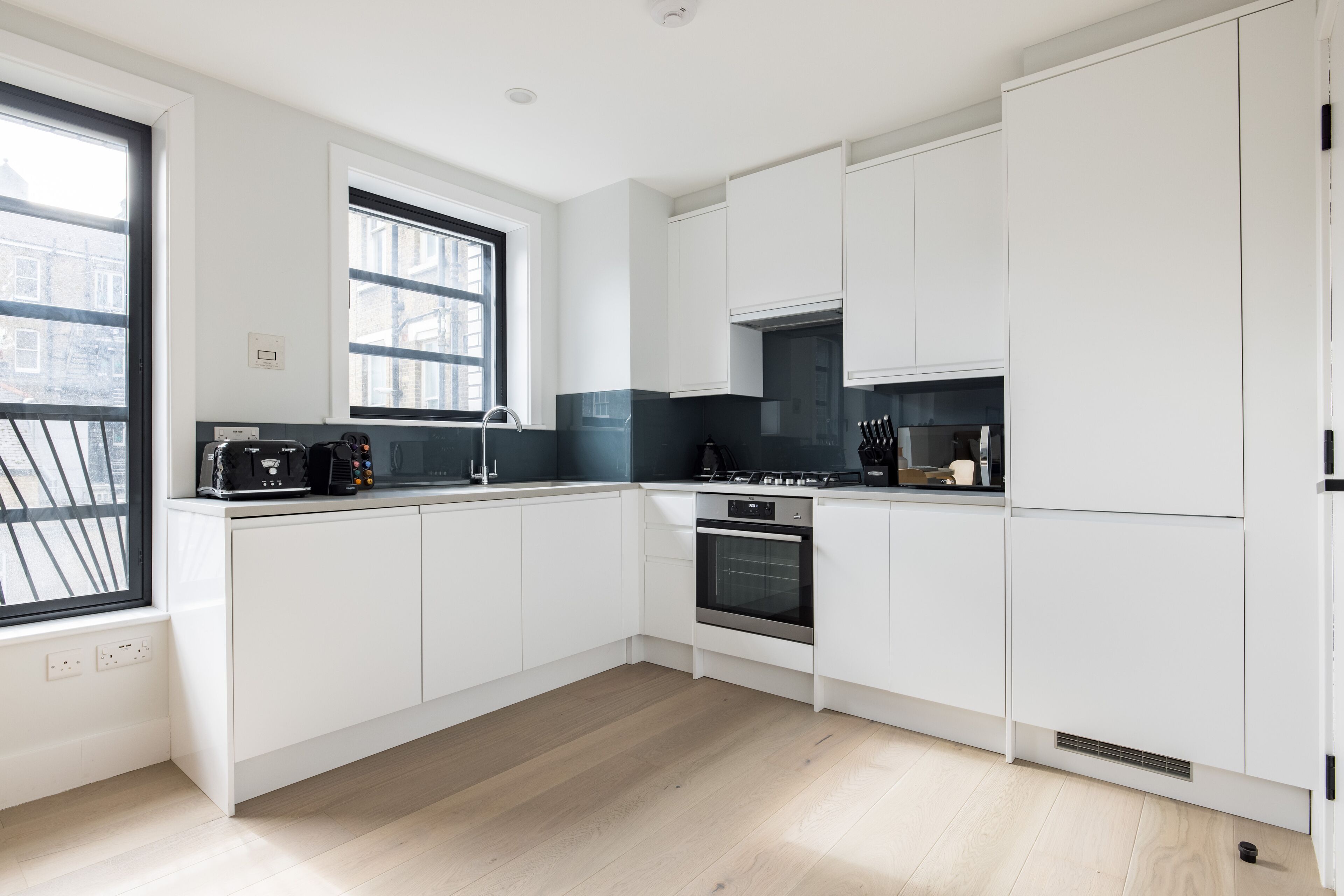 A modern kitchen with white cabinets, a built-in oven, and a window with a view of buildings.