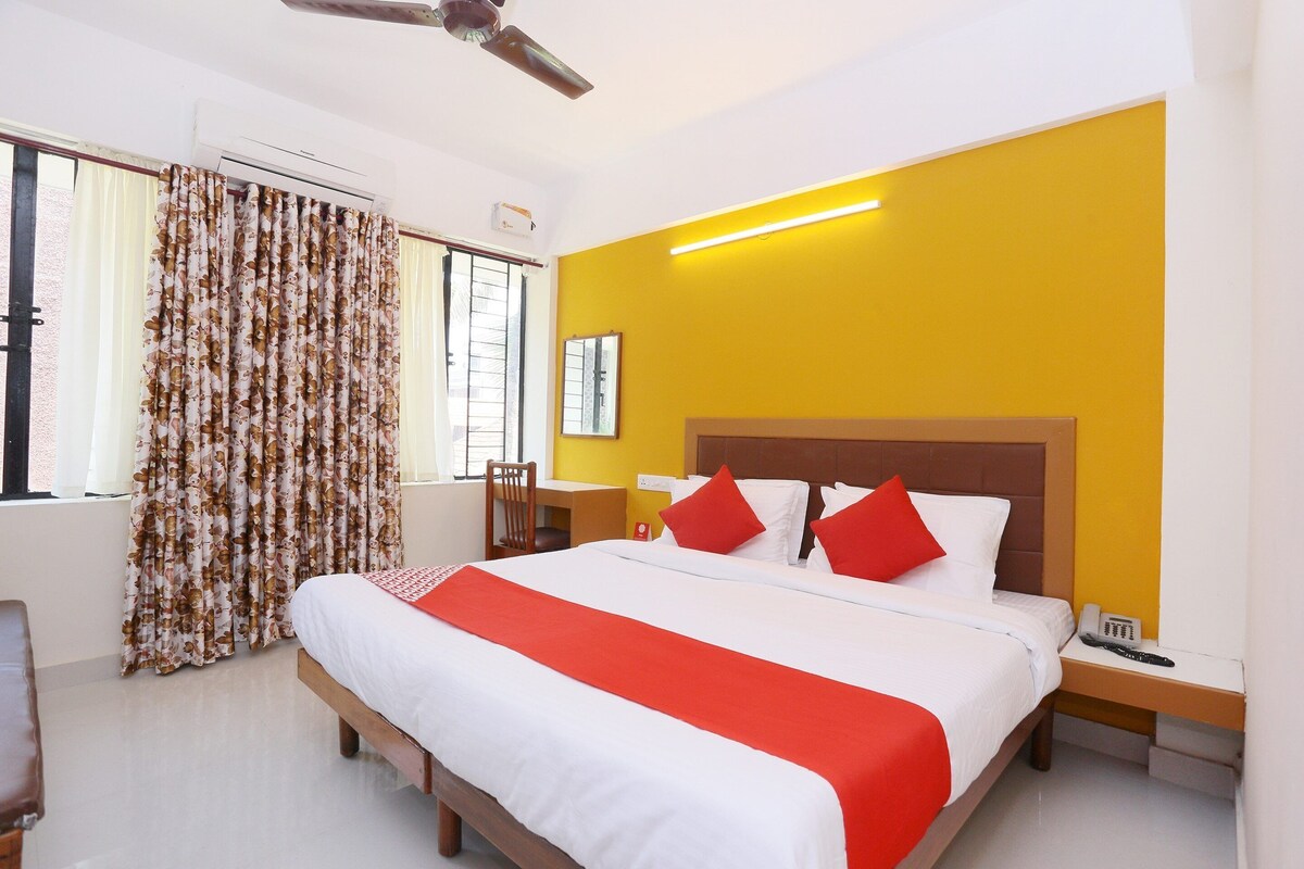 A hotel room with a bed, a desk, a chair, a nightstand, and a ceiling fan.