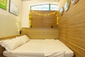A neatly made bed with white linens, a wooden headboard, and a window with a view of the sky.