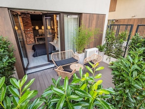 An outdoor patio with wicker furniture, a glass door entrance, and potted plants. - Loft House Premium Apartments (Wroclaw)