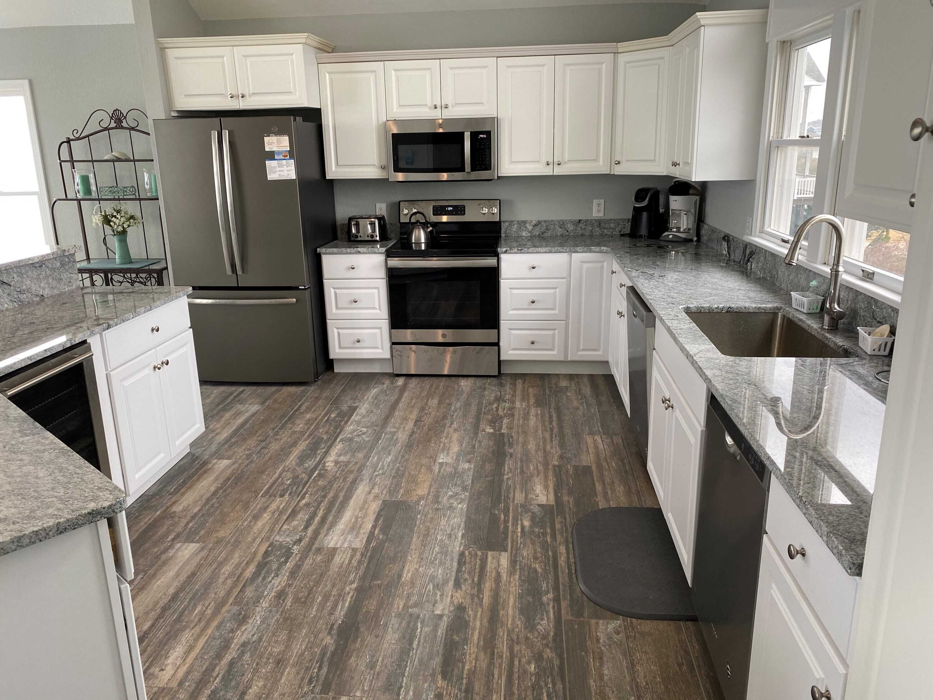 A modern kitchen with white cabinets, stainless steel appliances, and a granite countertop.