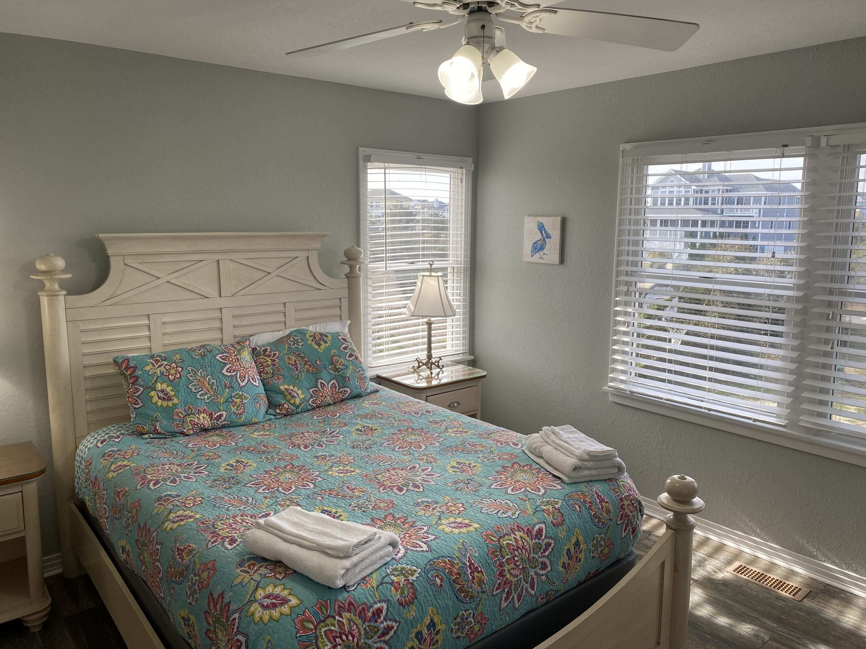 A bedroom with a bed, a nightstand, a lamp, and a window with blinds.