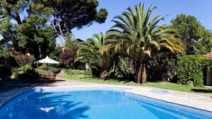 Une piscine entourée d’une végétation luxuriante et de palmiers.