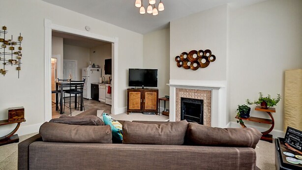 Una sala moderna con sofá, televisión, chimenea y decoración mural.