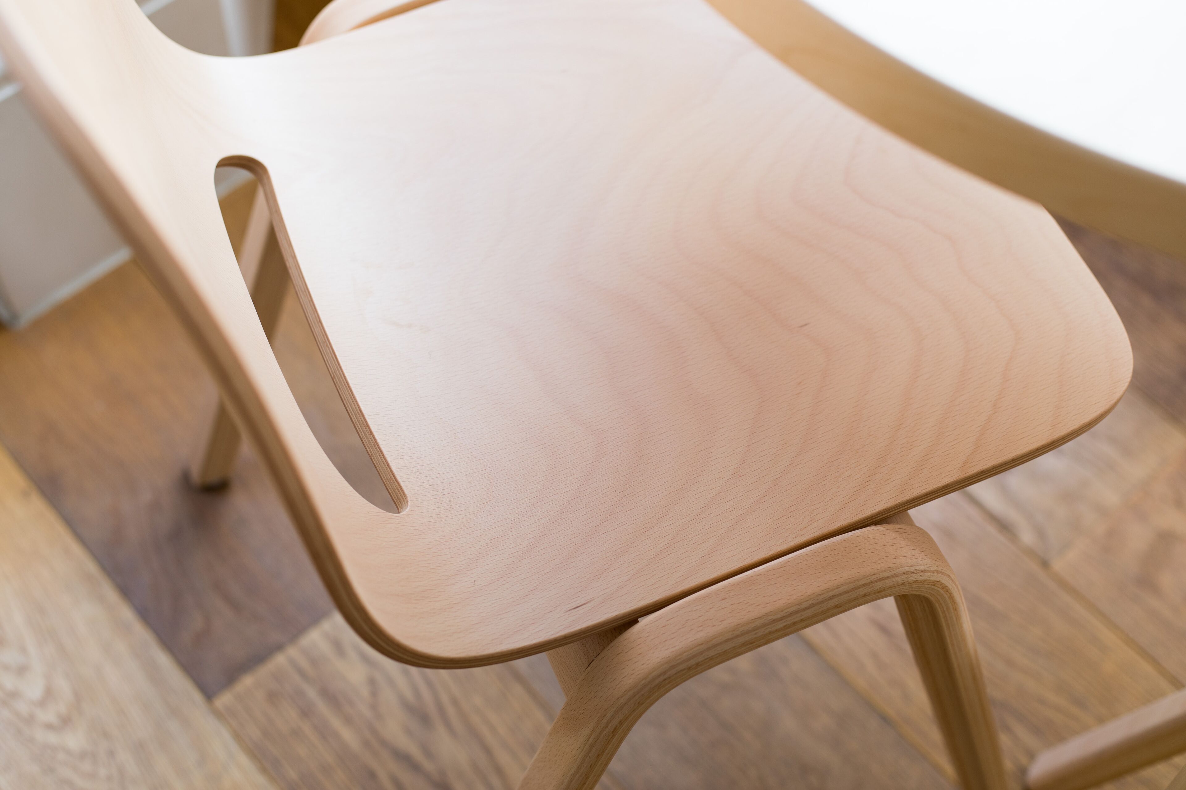 A wooden chair with a curved backrest and a cut-out on the side.
