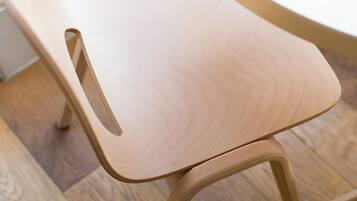 A wooden chair with a curved backrest and a cut-out on the side.