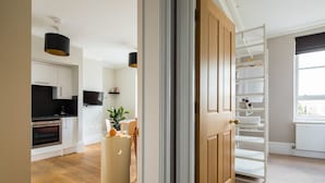 A modern kitchen with built-in appliances, a dining area with a plant, and a white shelving unit. - Hausd - Covent Garden (London)