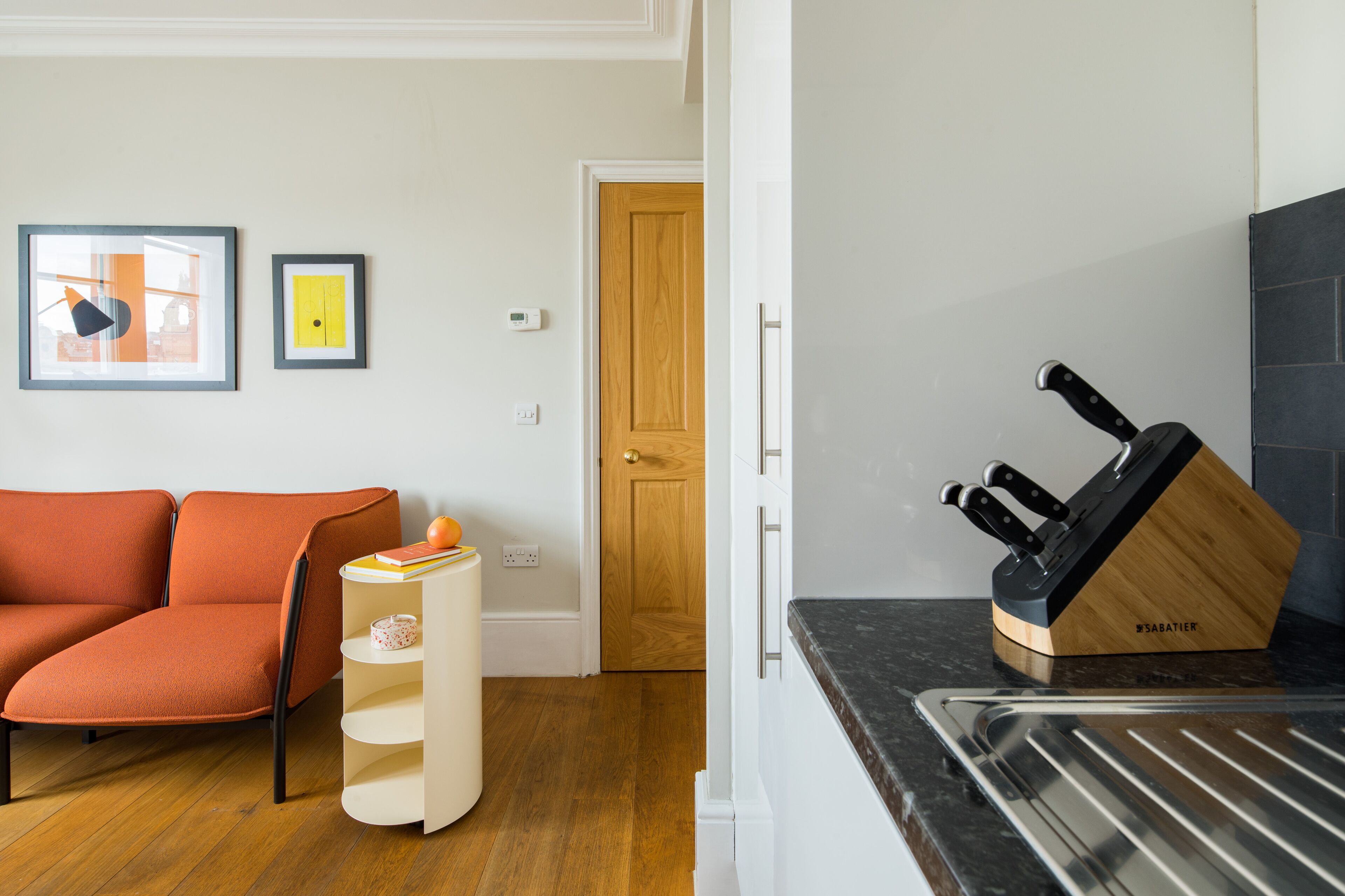 A modern kitchen with a black countertop, a knife block, and a wooden door.