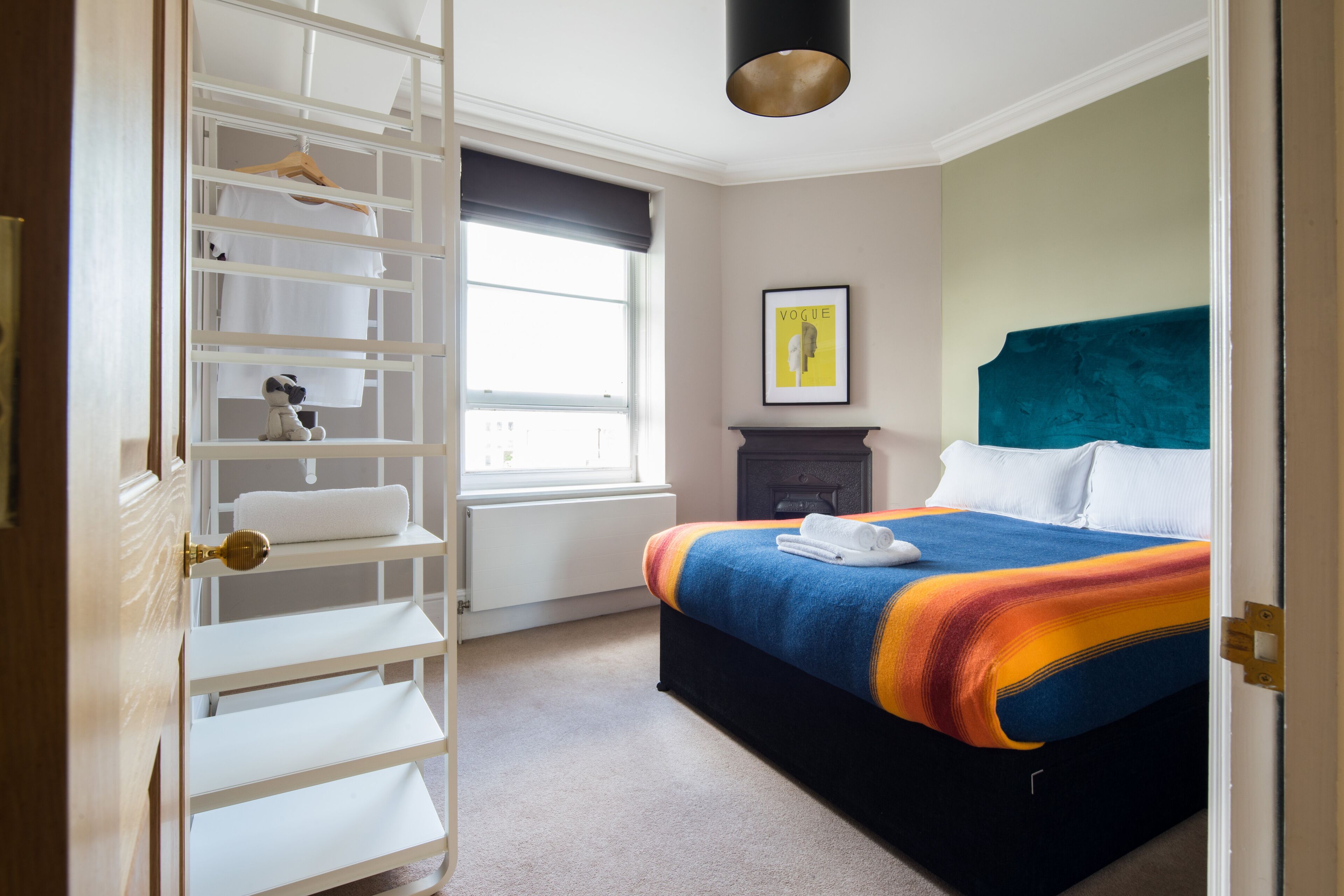 A bedroom with a bed, a wardrobe, a window, and a painting on the wall.