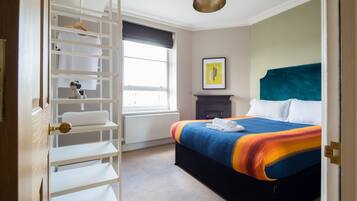 A bedroom with a bed, a wardrobe, a window, and a painting on the wall.