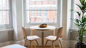 A room with a round table, two chairs, a potted plant, and a bed. - Hausd - Covent Garden (London)
