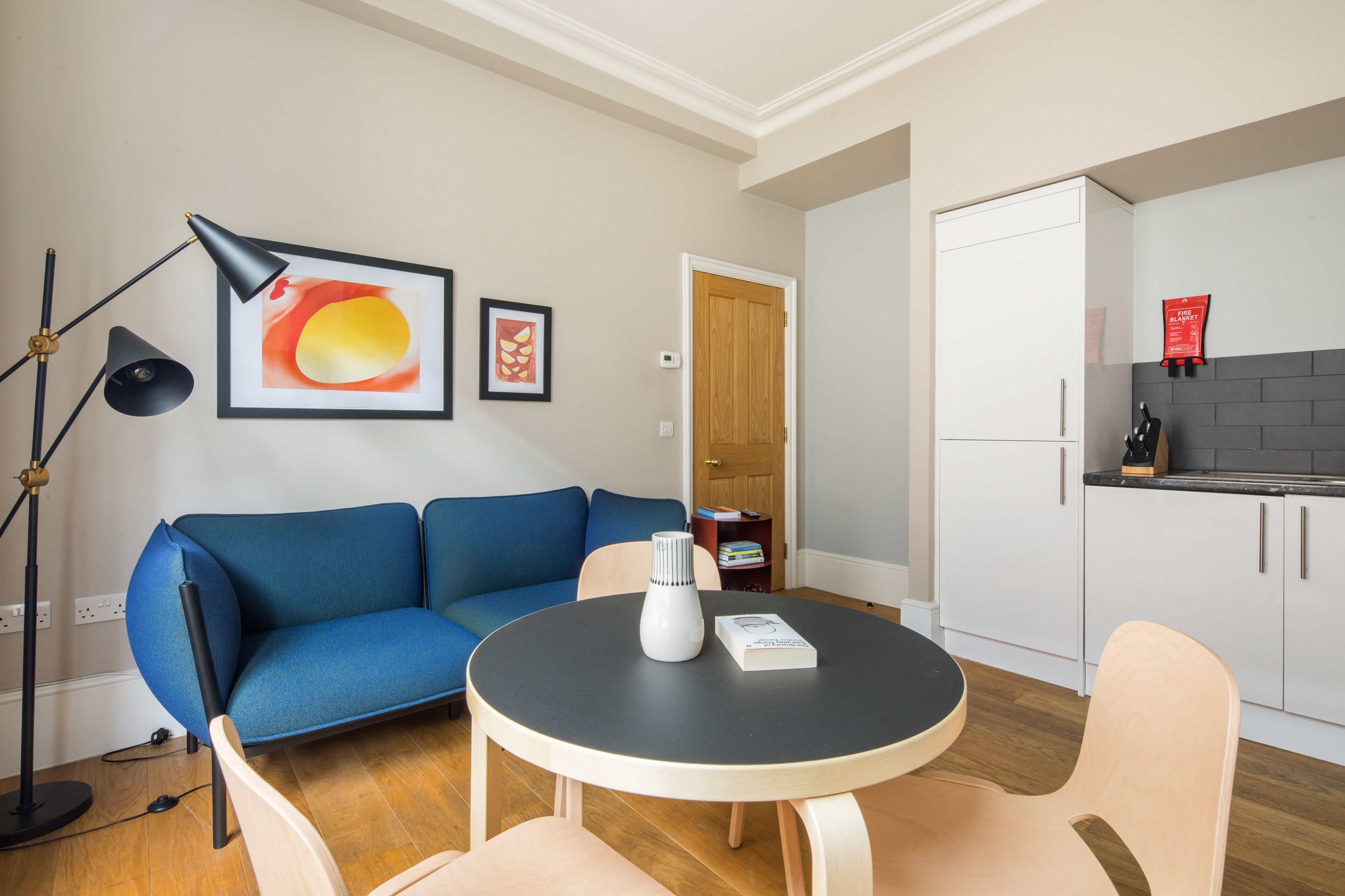 A modern living room with a blue sofa, a round table, and a floor lamp.