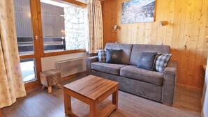 Une pièce chaleureuse avec un canapé gris, une table basse en bois et un mur en pierre.