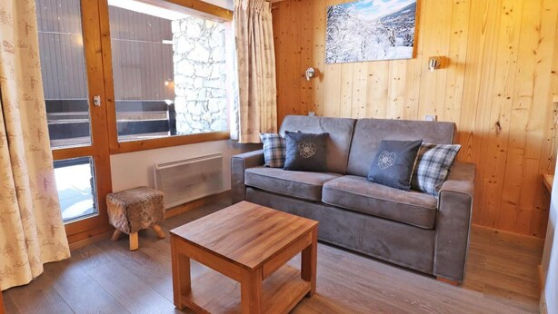 A cozy room with a grey sofa, a wooden coffee table, and a stone wall.