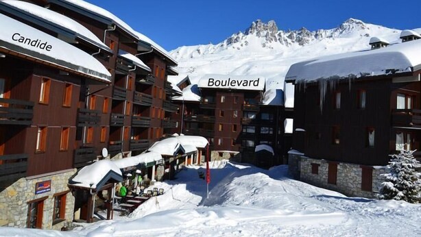 Un bâtiment enneigé portant l’inscription « Boulevard », avec une montagne en arrière-plan.