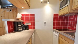 A compact kitchen with wooden cabinets, a microwave, a coffee maker, and a sink. - 10m from ski slopes, Ground floor, view limited, 27m², Méribel-Mottaret (Méribel - Les Allues)