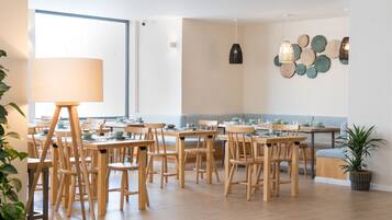 Un comedor con mesas y sillas de madera, una lámpara grande y una pared decorada con adornos circulares.