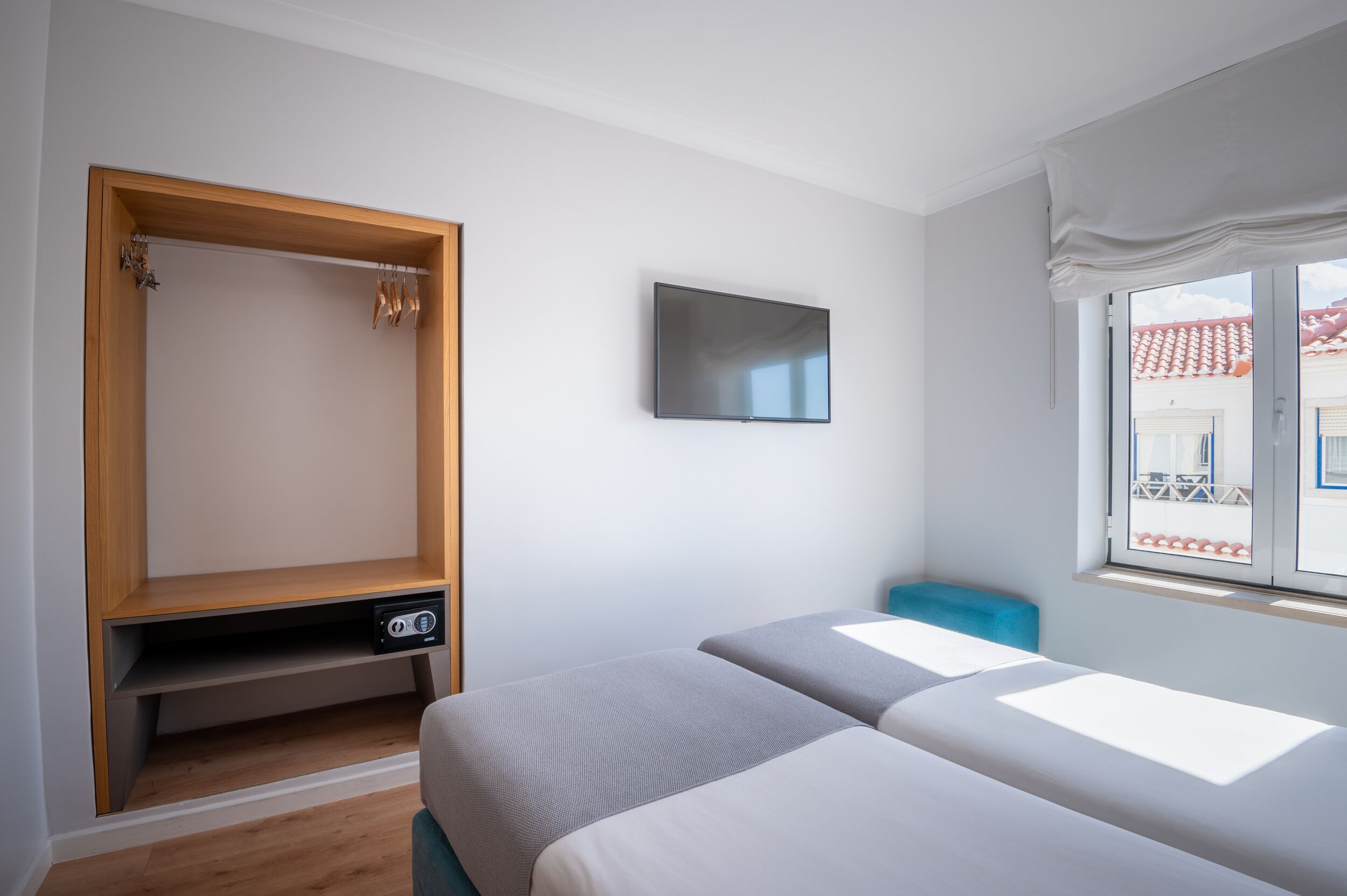 Un dormitorio con dos camas, un armario de madera, un televisor y una ventana con vistas.