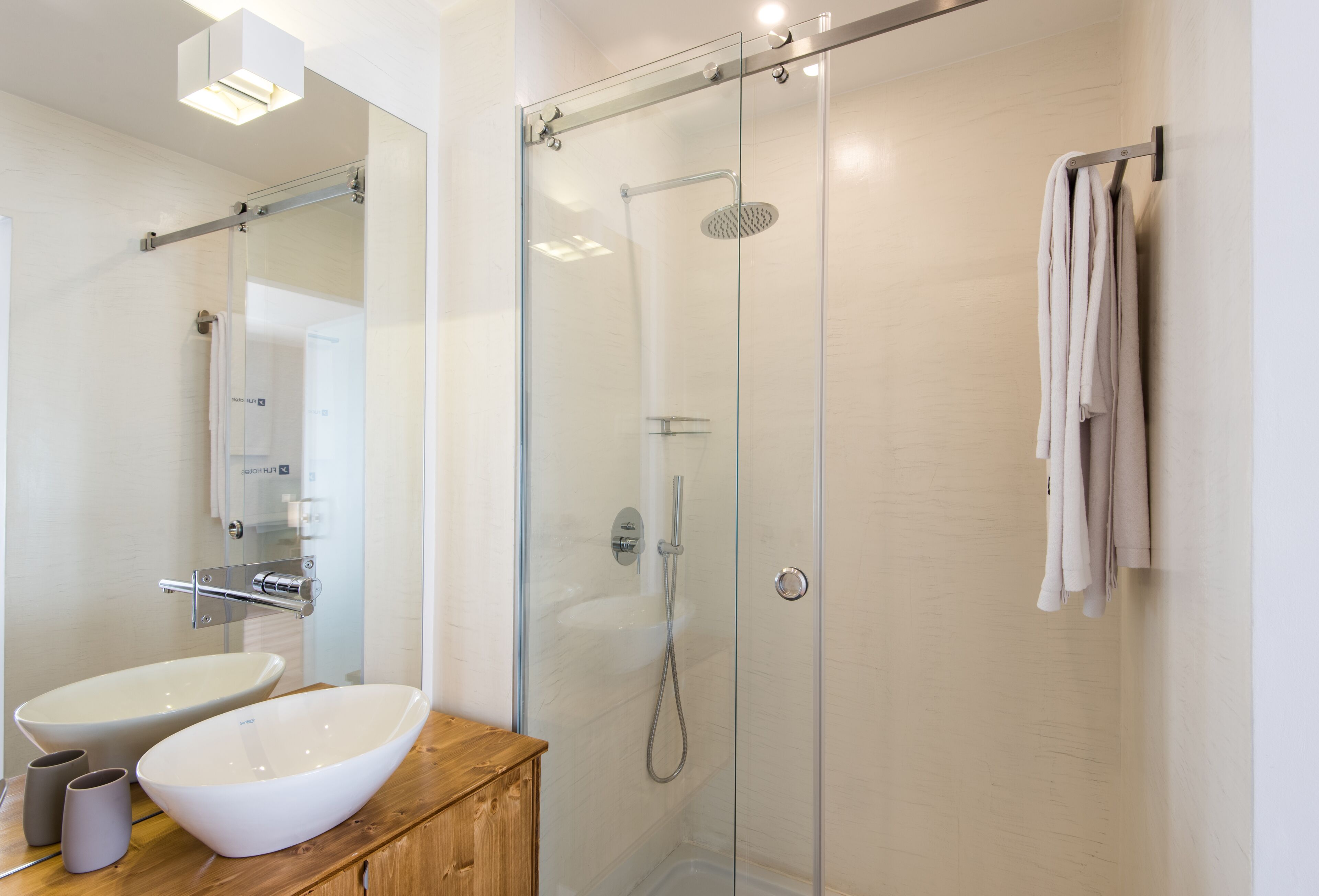 Ein modernes Badezimmer mit einer gläsernen Dusche, einem Holzlager und einem Waschbecken in einem Behälter sowie einem Handtuchhalter.