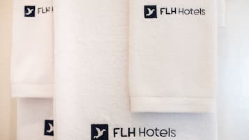 A stack of white towels with the FLH Hotels logo.