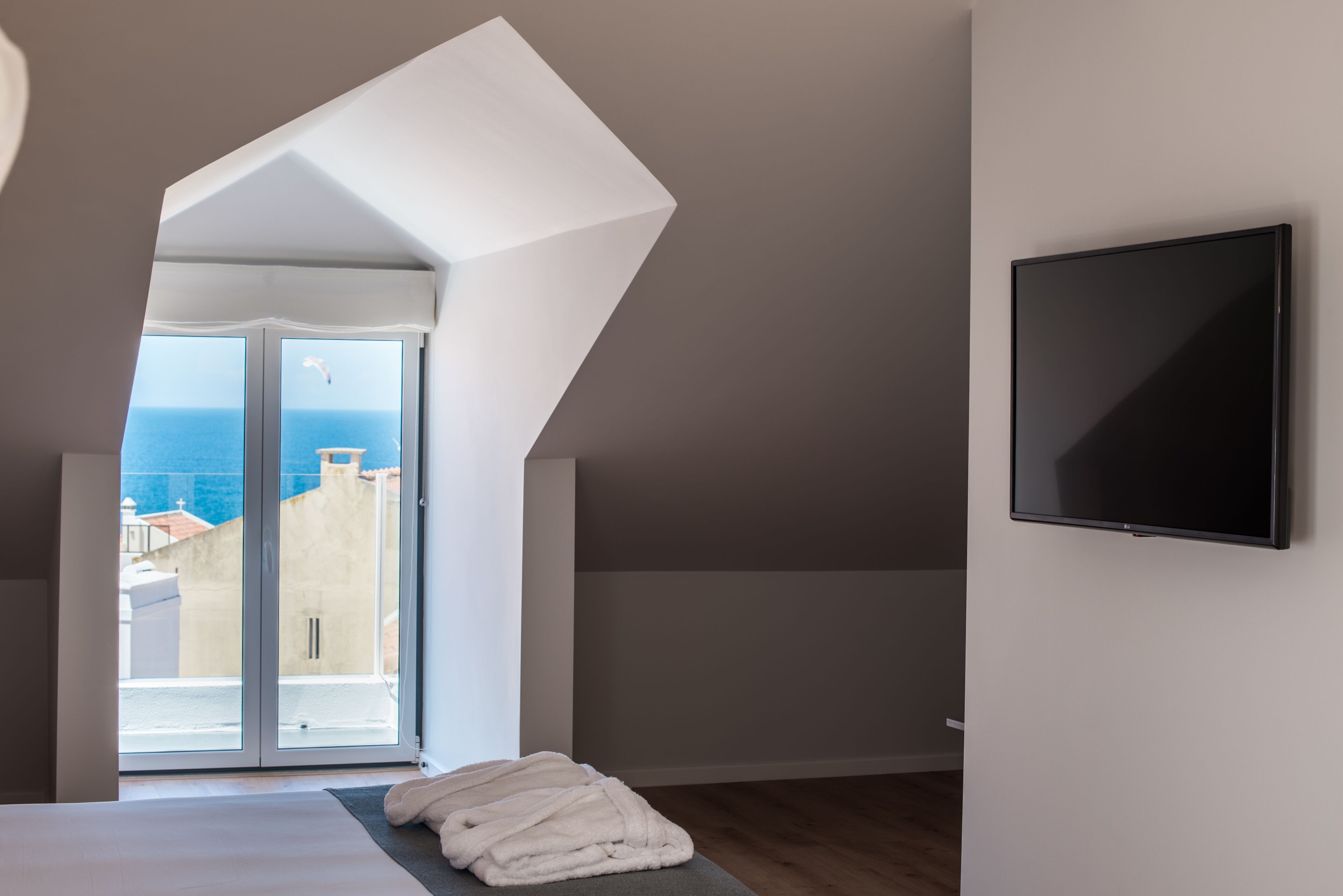 Un dormitorio con un ventanal grande, televisor de pantalla plana y vista al mar.