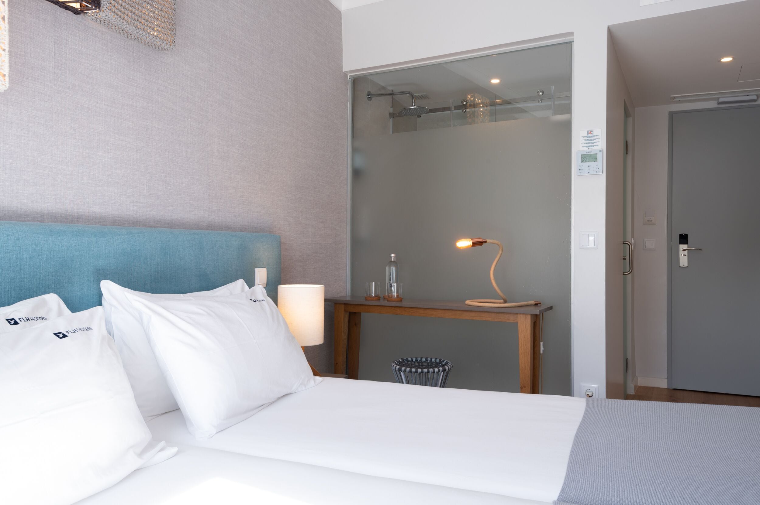 Une chambre d’hôtel équipée d’un lit, d’un bureau, d’une chaise, d’une lampe et d’un espace douche.