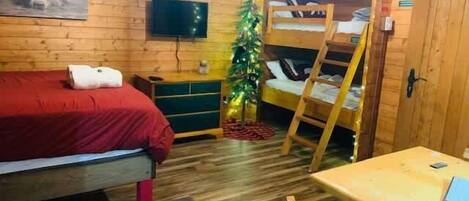 Een gezellige kamer met een stapelbed, een bureau, een televisie en een kerstboom.
