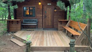 A wooden cabin with a porch, a bench, and a door marked with the number 15889.