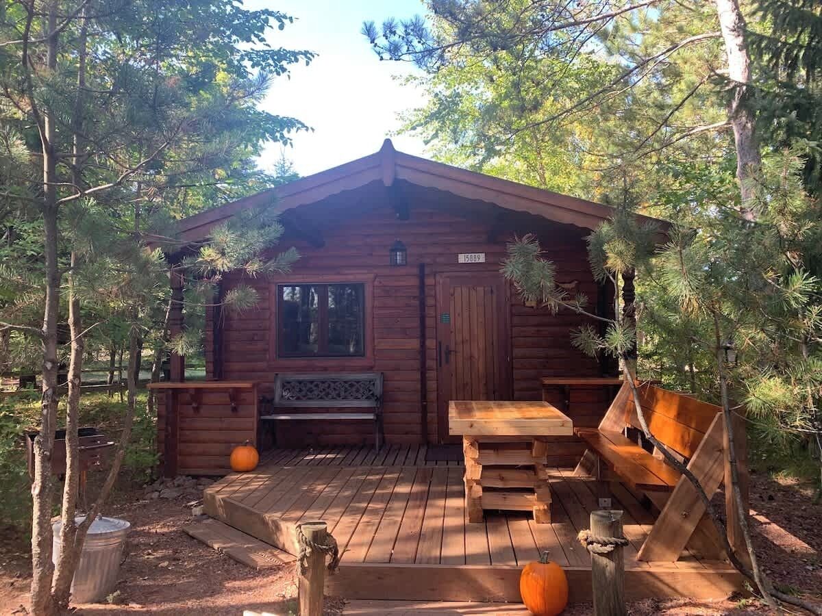 Un chalet rustique doté d’une terrasse en bois, d’un banc et d’une table.