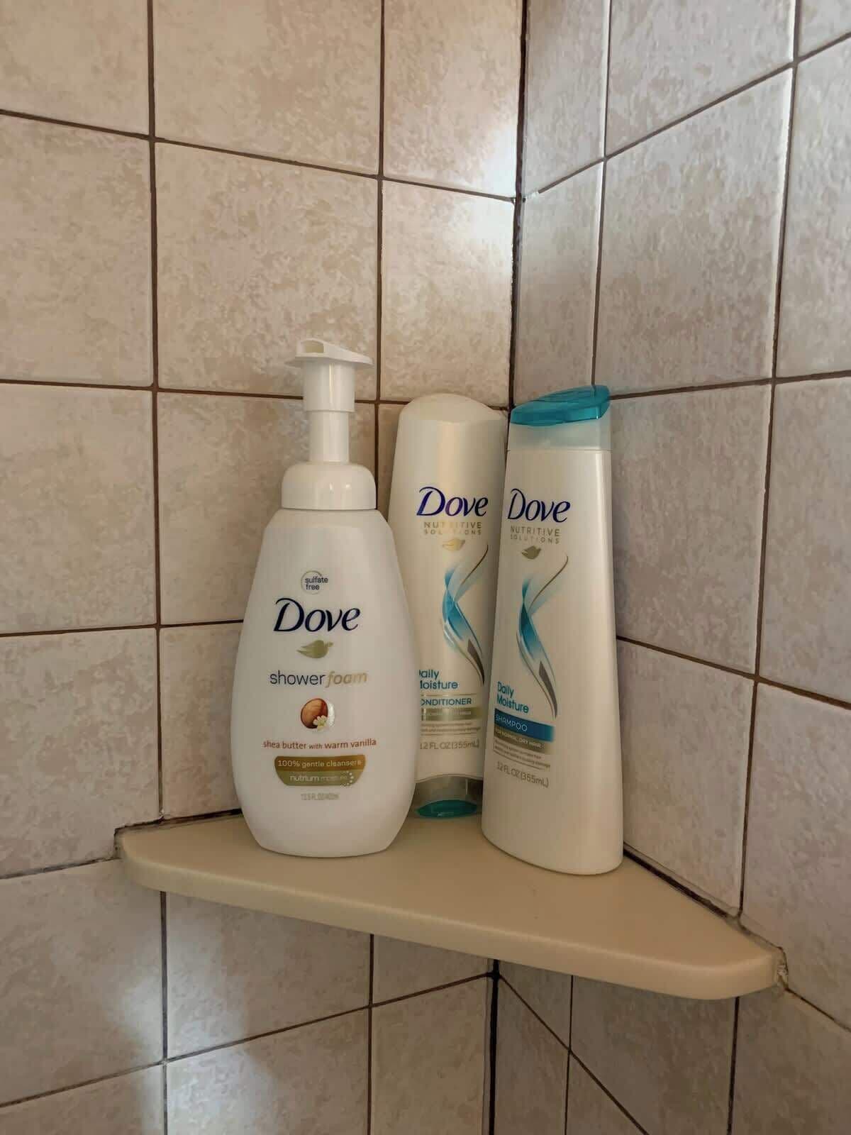 Een badkamerplank met Dove douchefoam, conditioner en shampoo.