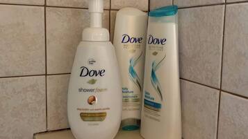 Een badkamerplank met Dove douchefoam, conditioner en shampoo.