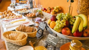 Een buffet met diverse gerechten, waaronder fruit, brood en gebak.