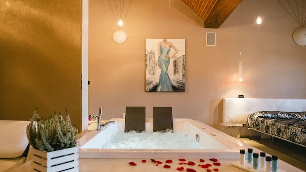 Een spa kamer met een bad, een schilderij aan de muur, en een bed met een geborduurd sprei.