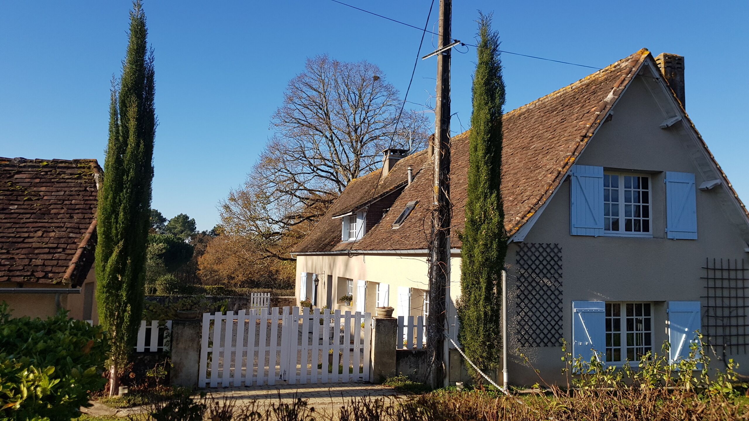 A two-story house with a sloped roof, white shutters, and a white picket fence.