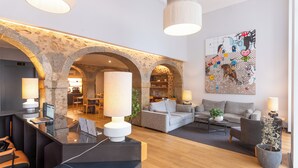 A modern lobby with stone arches, a reception desk, seating area, and a large abstract painting. - Urbano FLH Hotels Lisboa (Lisbon)