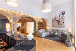A modern lobby with stone arches, a reception desk, seating area, and a large abstract painting.