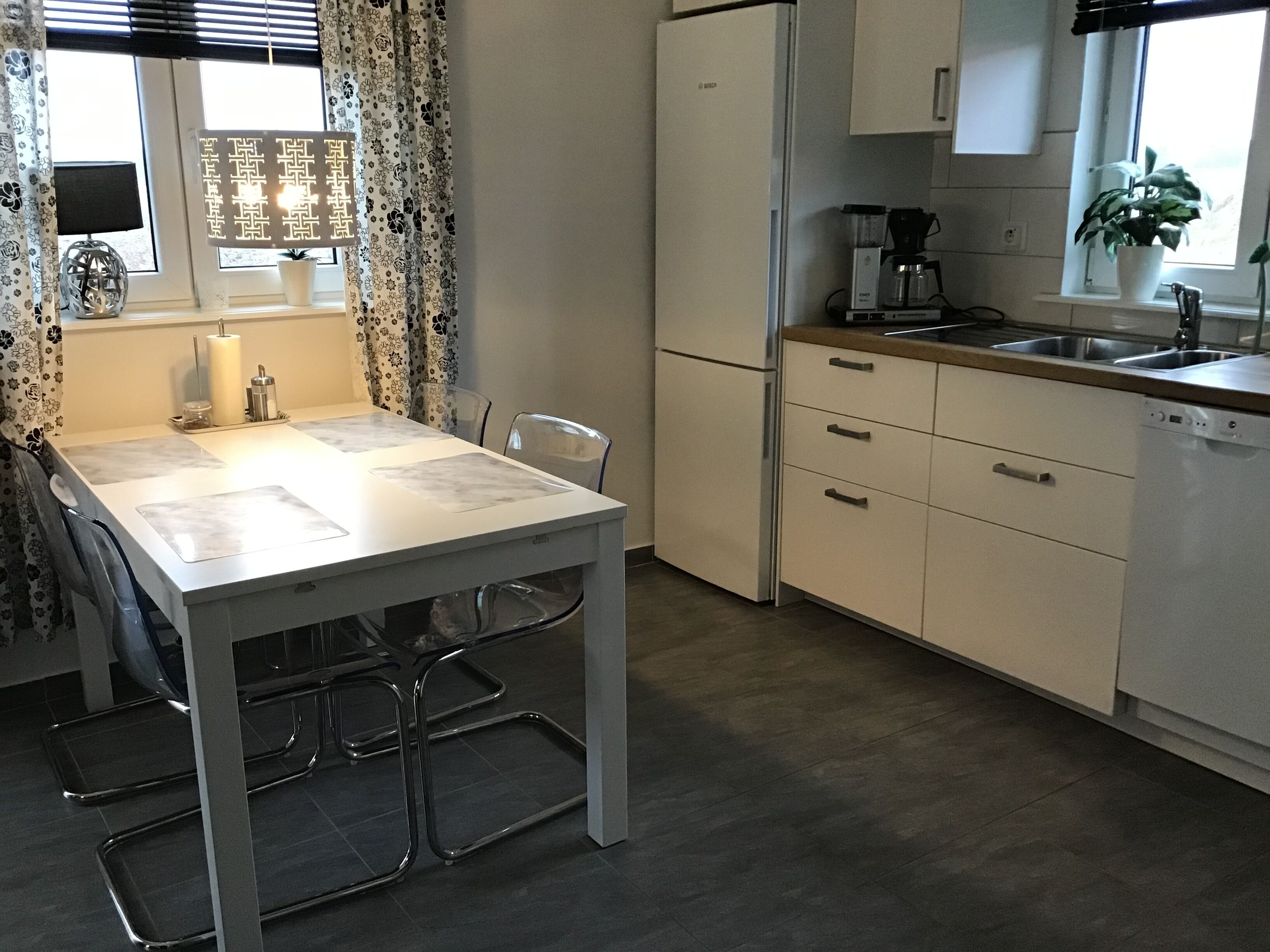 A modern kitchen with a white refrigerator, a coffee maker, and a sink.